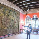 El gerente del Palacio de Las Dueñas explica a los periodistas la composición del tapiz