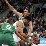 El ala-pívot mexicano del Real Madrid, Gustavo Alfonso Ayón (c), defendido por los jugadores del Laboral Kutxa Baskonia, el pívot bosnio Darko Planinic (d) y el alero húngaro Adam Hanga