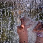 Unos jóvenes se bañan en una de las fuentes públicas de la avenida del Libertador en el centro de Córdoba.