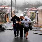 Un miembro de los equipos de rescate ayuda ayer a unos vecinos de Guayama, en Puerto Rico