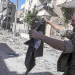 Un miliciano que participó en la derrota del EI en Raqa muestra una bandera yihadista