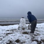 Un hombre hace un muñeco de nieve. Imagen de archivo
