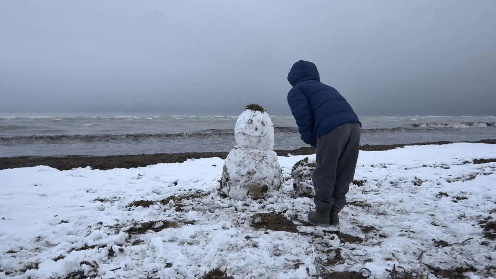 Un hombre hace un muñeco de nieve. Imagen de archivo
