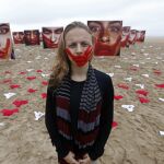 Imagen de 2016 de una voluntaria de la ONG Río de Paz posa en la playa de Copacabana junto a imágenes de modelos que representan a mujeres que sufrieron algún tipo de abuso sexual