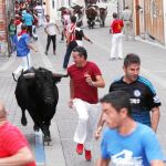 Un mozo corre delante del único novillo que entró en la plaza en el encierro de ayer en Cuéllar. A la derecha, momento en el que una excavadora retira a uno de los animales fallecidos