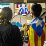 Un grupo de jóvenes, entre ellos uno luciendo una estelada, sigue por televisión el discurso del Rey a la Nación pronunciado el pasado 3 de octubre
