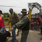Fotografía cedida por prensa de la Vicepresidencia de Venezuela, de un miembro de la Guardia Nacional Bolivariana (GNB) da indicaciones a un grupo de ciudadanos que cruzan el puente internacional "La Union"