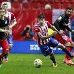 El centrocampista del Sporting de Gijón Jonathan Rodríguez (c) con el balón ante los jugaores del Athletic Iker Muniain (i) y Mikel Balenziaga (d), durante el partido de la jornada vigésima octava de Liga de Primera División celebrado en el estadio del Molinón de Gijón