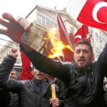 Partidarios de Erdogan queman un billete de dólar americano en una protesta contra Holanda en Estambul