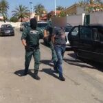 Imagen de dos agentes custodiando a uno de los detenidos