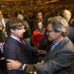 El presidente de la Generalitat Carles Puigdemont saluda al expresidente, Artur Mas, en presencia de la presidenta del parlamento catalán, Carme Forcadell, durante el acto central del Pacto Nacional por el Referéndum