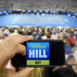 Un aficionado en la central del Abierto de Australia muestra uno de los principales patrocinadores del torneo, la casa de apuestas William Hill