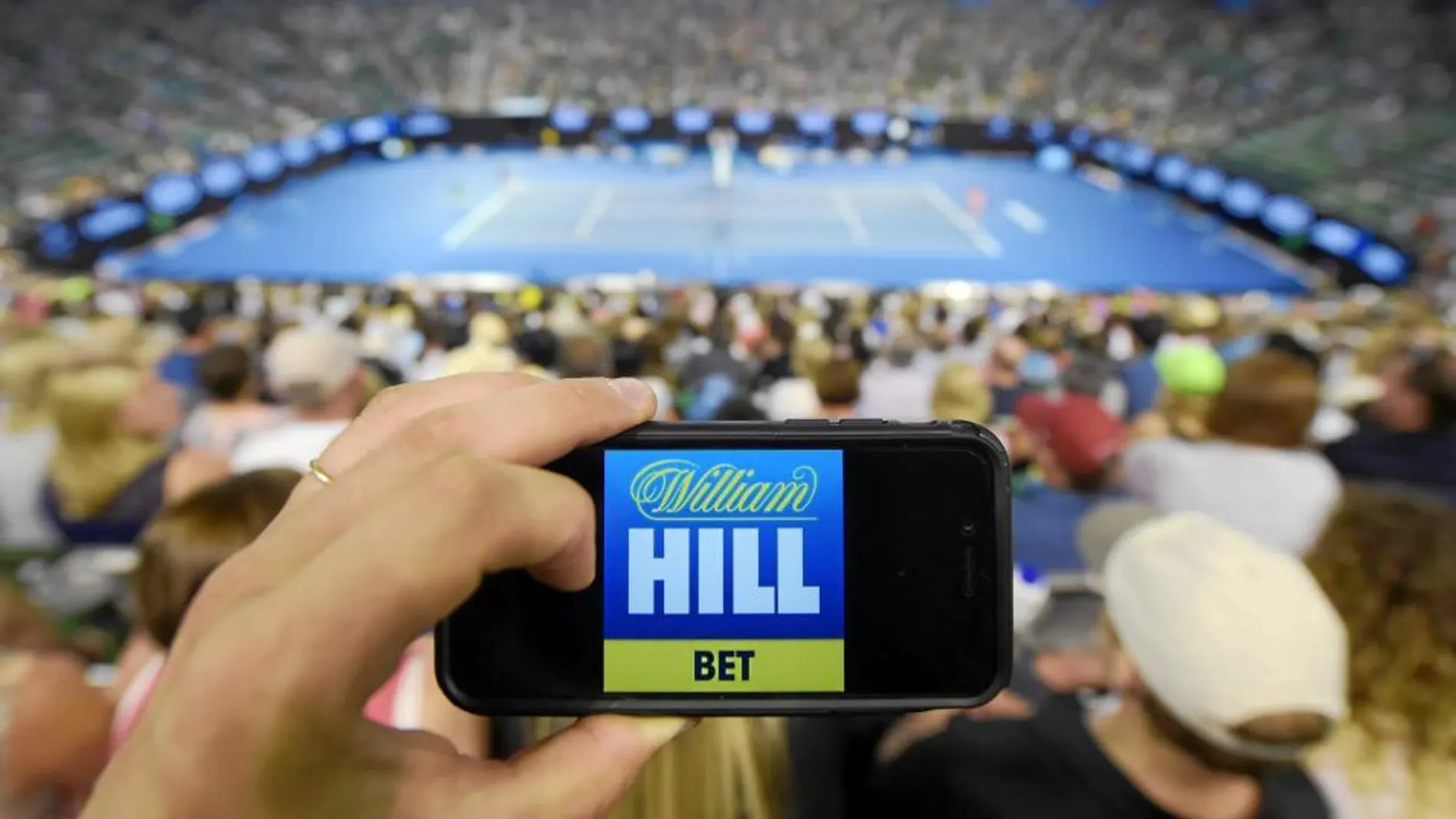 Un aficionado en la central del Abierto de Australia muestra uno de los principales patrocinadores del torneo, la casa de apuestas William Hill