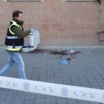 Un policía pasa junto a un charco de sangre en el lugar en el que cayó la mujer