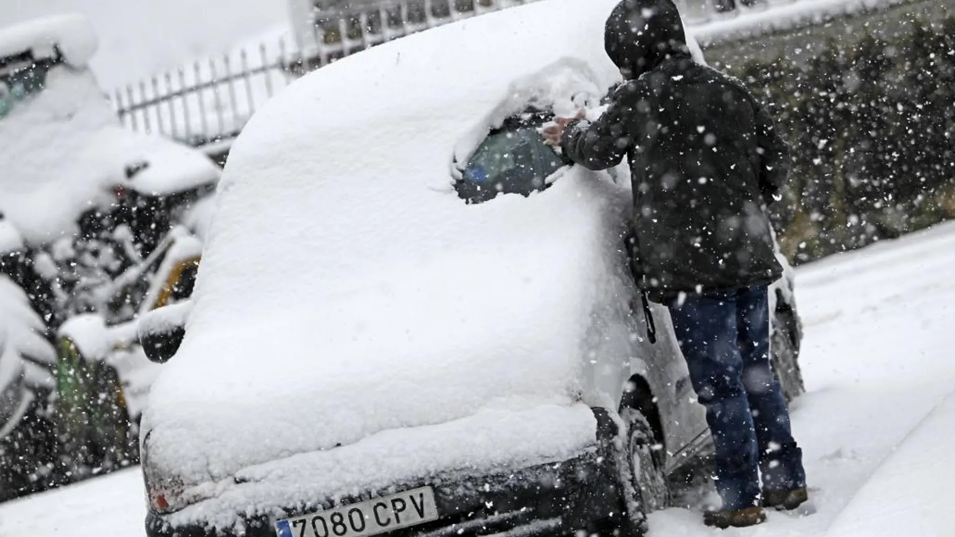 Una persona trata de limpiar su coche de la nieve caída en la localidad de Lecumberri