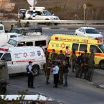 Policías y soldados israelíes inspeccionan la zona en que ha tenido lugar el atropello.