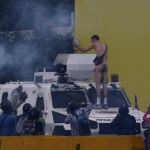 Un hombre desnudo permanece subido a un vehículo de la Guardina Nacional Bolivariana hoy en Caracas.