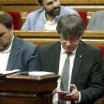 El presidente de la Generalitat, Carles Puigdemont (d), y su vicepresidente, Oriol Junqueras, durante el pleno del Parlament