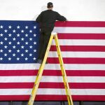 Un trabajador coloca una bandera en la Universidad de Hooksett antes de un acto de Hillary Clinton