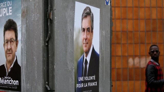 Carteles de François Fillon (C) y Jean-Luc Melenchon