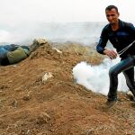 40.000 manifestantes. Un palestino con una onda corre mientras otros buscan refugio en el primer aniversario de la Gran Marcha del Retorno, ayer en el este, frente al muro fronterizo