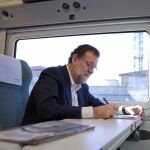 El presidente del Partido Popular y presidente en funciones del Gobierno, Mariano Rajoy, tomando notas en el tren en el que viaja hacia Zamora