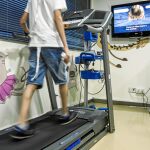 La sala de rehabilitación infantil durante una de las sesiones en las que los niños hacen ejercio de forma controlada sobre una cinta para correr frente a una pantalla de videoconsola