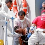 Personal médico de la Marina italiana socorre ayer a una mujer a su llegada al puerto italiano de Reggio Calabria