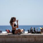 Una joven disfruta del sol en la Playa de la Malvarrosa de València