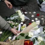 Una mujer deja una vela y lee un mensaje en la puerta de la sala Bataclan, objetivo yihadista en 2015