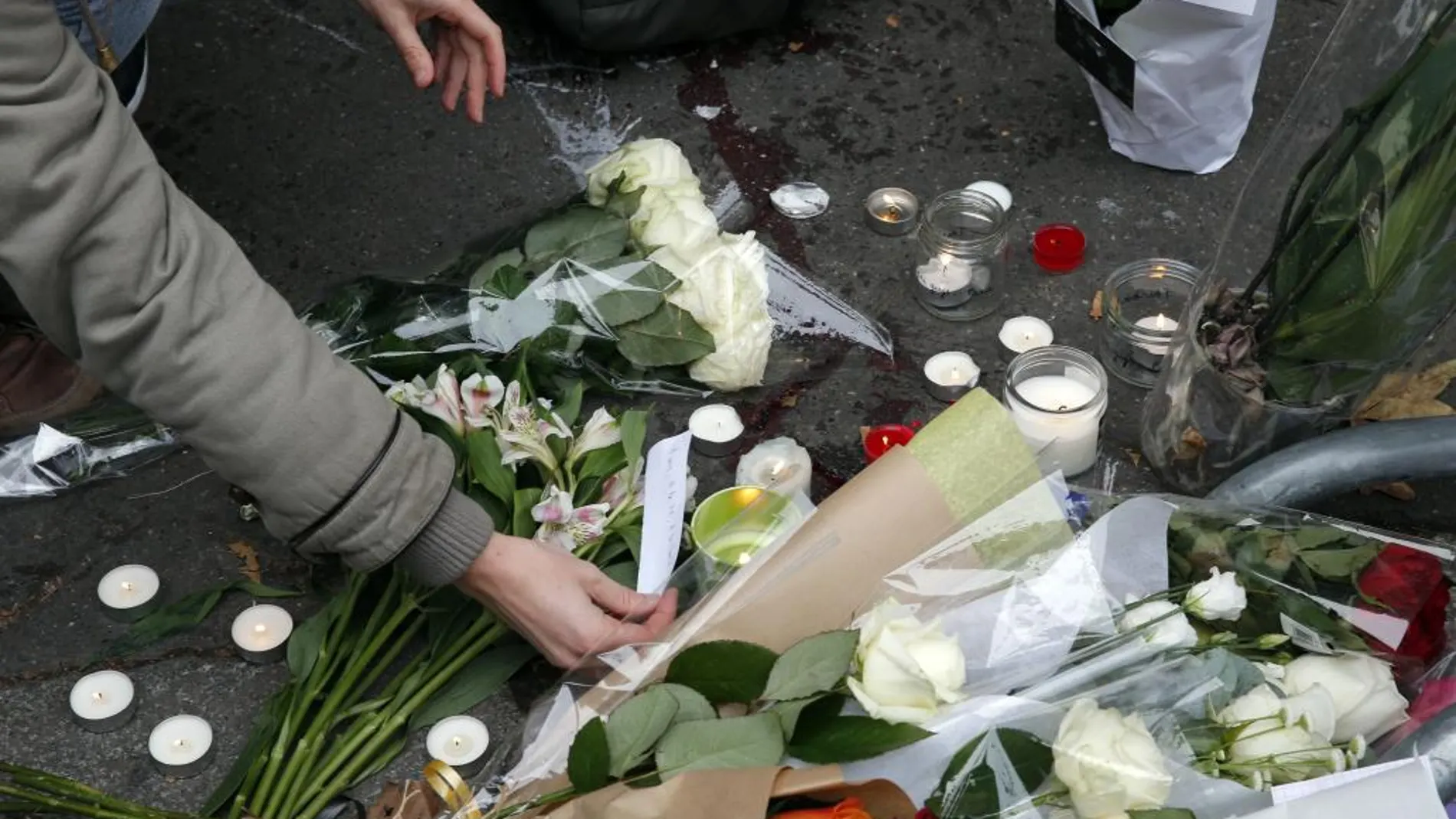 Una mujer deja una vela y lee un mensaje en la puerta de la sala Bataclan, objetivo yihadista en 2015