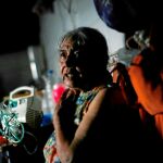 Una anciana sentada junto a su máquina nebulizadora apagada en el barrio de Caracas / Reuters