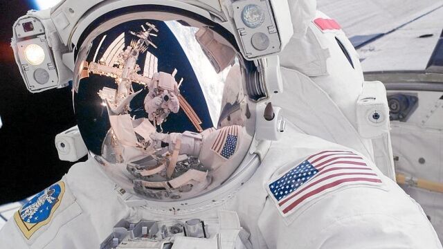 El casco del astronauta Mike Fossum en el que se refleja la Tierra, la Estación Espacial Internacional y su compañero Ron Garan