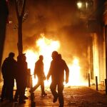 Contenedores incendiados en la calle Mesón de Paredes con la calle del Oso, en el barrio de Lavapiés de Madrid, tras la muerte de un mantero de un paro cardíaco. EFE/JAVIER LIZÓN