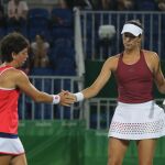 La española Carla Suárez (i) saluda a su compañera Garbiñe Muguruza (d) ante la pareja brasileña compuesta por Paula Goncalves y Teliana Pereira durante el partido de dobles