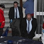 Miembros de los servicios funerarios con el cuerpo de uno de los miembros del matrimonio hallados muertos con signos de violencia en su piso.
