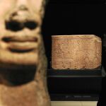 En primer plano, un capitel con la forma de la diosa Hathor procedente del templo de Bastet. Al fondo, un relieve del faraón Osorkon II que formó parte de un portal también del templo de Bastet