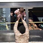Una mujer da su bebé a un militar a su llegada a un campo de refugiados