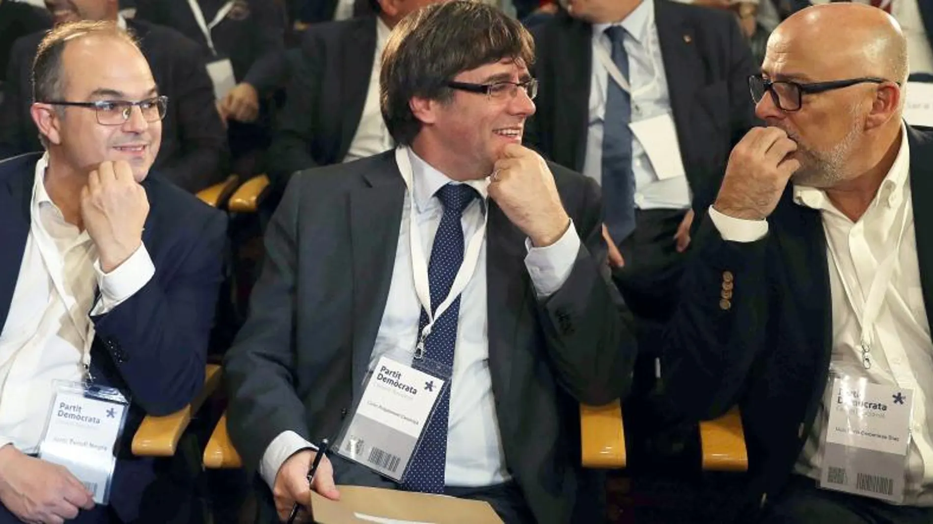 El presidente de la Generalitat, Carles Puigdemont (c), junto al conseller de la Presidencia Jordi Turull (i), y el presidente del grupo parlamentario de JxS, Lluís Corominas (d), al inicio de la reunión extraordinaria del consell nacional del PDeCAT. EFE/Toni Albir