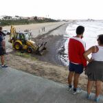 Una excavadora recoge el vertido en la arena de la playa de la Concha en Algeciras