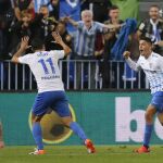 El centrocampista del Málaga Pablo Fornals (2d) celebra su gol, primero del equipo, junto a sus compañeros el defensa Juankar Pérez (d), y el centrocampista "Jony"Rodríguez, ante el defensa del Sporting Lillo (i)