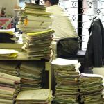 Un funcionario trabaja junto a varias pilas de expedientes