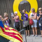 Turistas fotografían a un ciudadano que pasea envuelto en una estelada