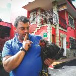Fernando, dueño del gallinero que el Ayuntamiento quiere clausurar, posa con una de sus aves frente al hotel que denunció los cacareos. Foto: Nacho Cubero