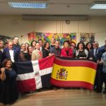 Genaro Roble (Yiyoh) y Sarah Merán, autores del proyecto «Lienzos Sueltos por La Paz» posando en una foto de familia, mostrando las banderas de R. Dominicana y de España