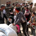 Un niño lleva un retrato del presidente sirio, Bachar al Asad, mientras abandona, junto a cientos de civiles, la zona de Guta Oriental, en la zona rural de Damasco
