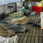 Varios migrantes yacen sobre una embarcación tras llegar irregularmente a España