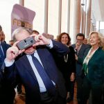 El presidente de la Junta prueba unas gafas adaptadas a modo visor a un móvil en el pabellón de Madrid de AR&amp;PA.
