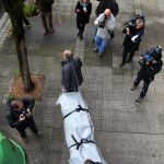 Trabajadores de servicios funerarios trasladan el cuerpo de una de las dos víctimas