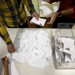 El presidente de una mesa electoral deposita los votos de la urna sobre una mesa para proceder a su recuento